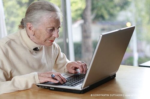 Elderly lady typing on laptop. Shallow DOF. by Konstantin Sutyagin.